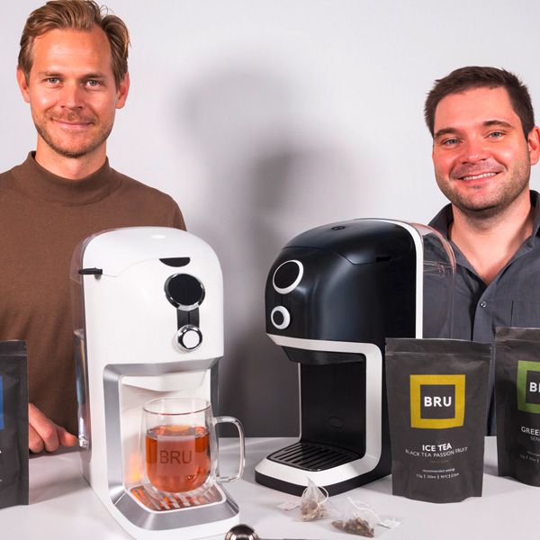 Les deux fondateurs de la BRU se tiennent devant une machine à thé blanche et une machine à thé noire.