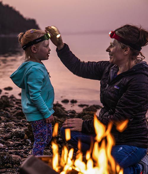 Frau mit Kind mit BioLite Stirnlampe sitzen an Feuerstelle