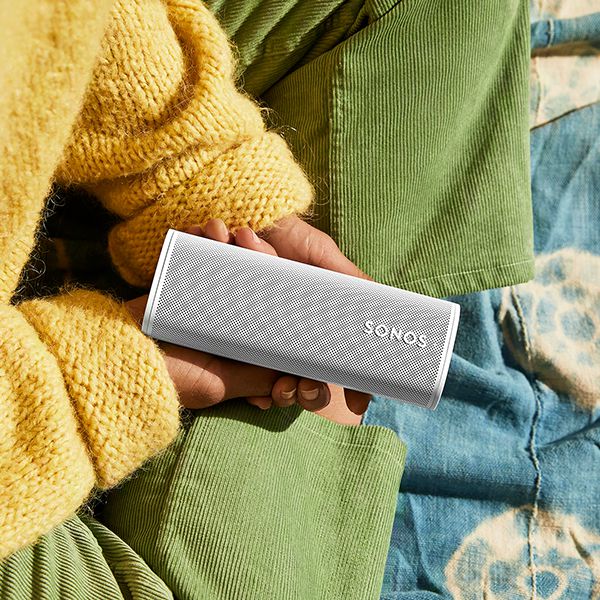 Eine Sonos Roam 2 in den Händen eines Mädchens mit einem gelben Pullover