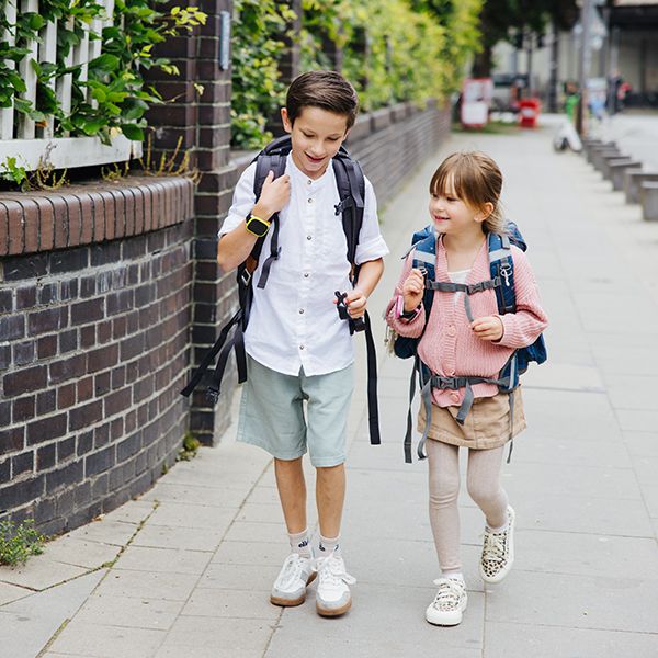 Zwei Kinder laufen zur Schule mit Xplora Smartwatches