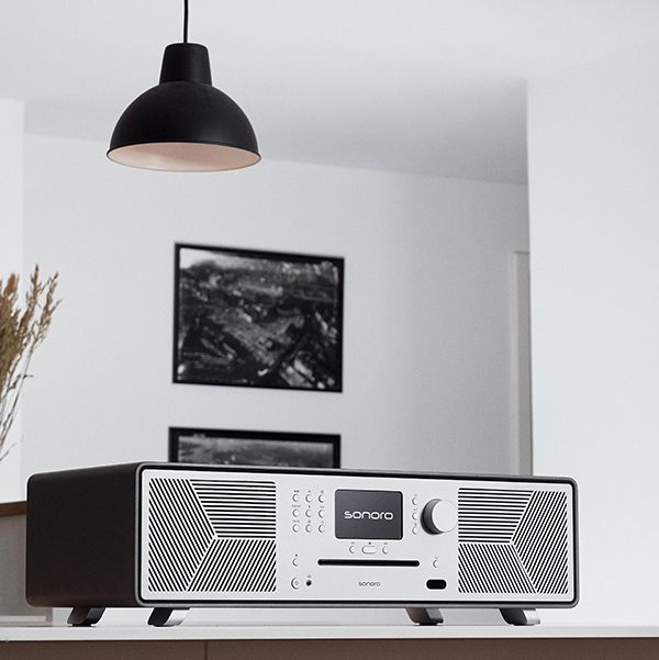 Lifestyle Bild des Sonoro Meisterstück Gen. 2 Lautsprechers auf einer weissen Holzfläche unter einer schwarzen Hängelampe